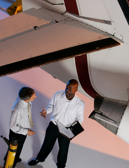 Two men talking in airplane hangar