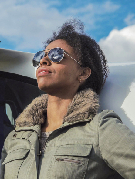 Female Black pilot in front of plane